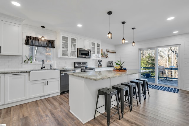 kitchen featuring stainless steel appliances, sink, a kitchen island, and white cabinets