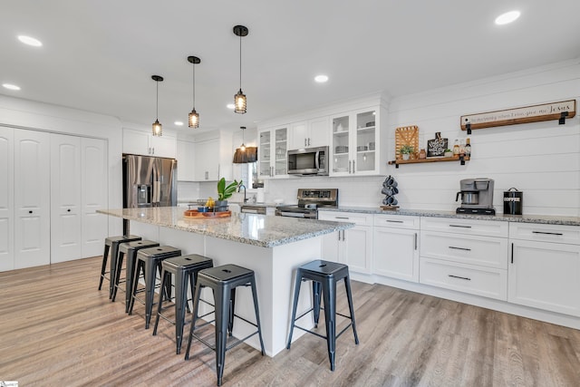 kitchen with a kitchen island, appliances with stainless steel finishes, light wood-type flooring, and white cabinetry