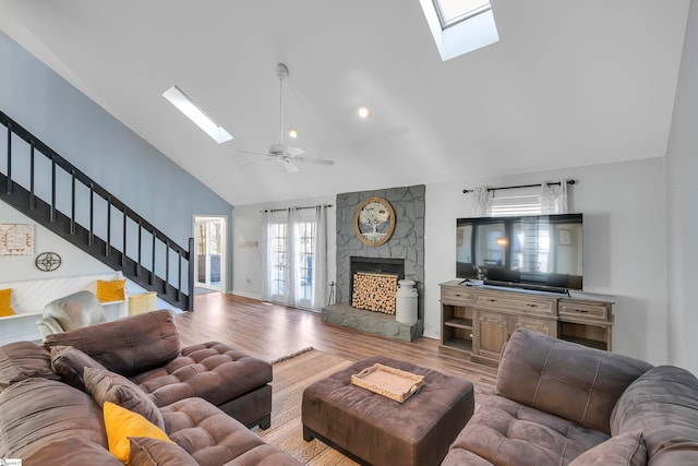 living room featuring hardwood / wood-style floors, a stone fireplace, high vaulted ceiling, and ceiling fan