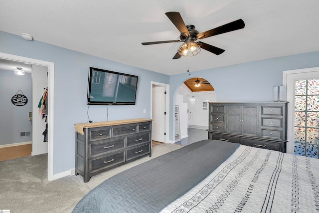 carpeted bedroom featuring connected bathroom, ceiling fan, and a textured ceiling