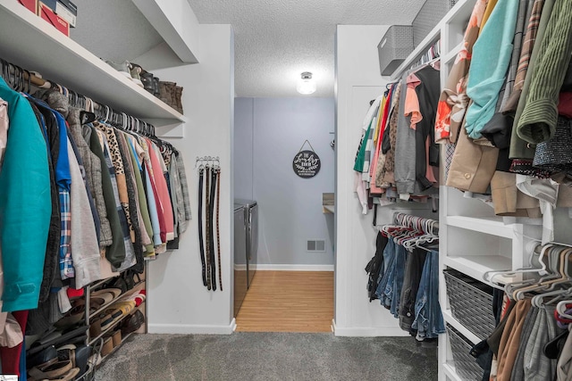 walk in closet featuring washing machine and dryer and dark hardwood / wood-style flooring