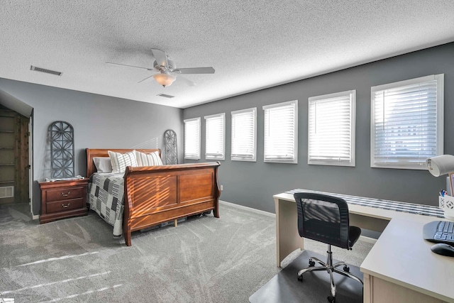 carpeted bedroom featuring a textured ceiling, multiple windows, and ceiling fan