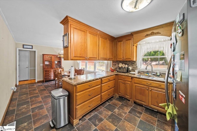 kitchen with stainless steel fridge, sink, kitchen peninsula, and a healthy amount of sunlight