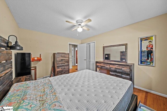 bedroom featuring hardwood / wood-style floors, a textured ceiling, a closet, and ceiling fan