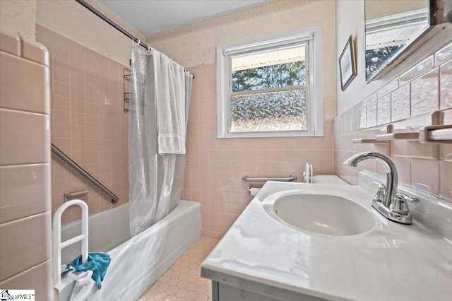 bathroom with vanity, shower / bathtub combination with curtain, a textured ceiling, and tile walls