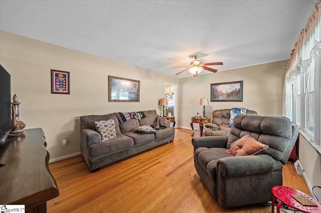 living room featuring a textured ceiling, light wood-type flooring, and ceiling fan