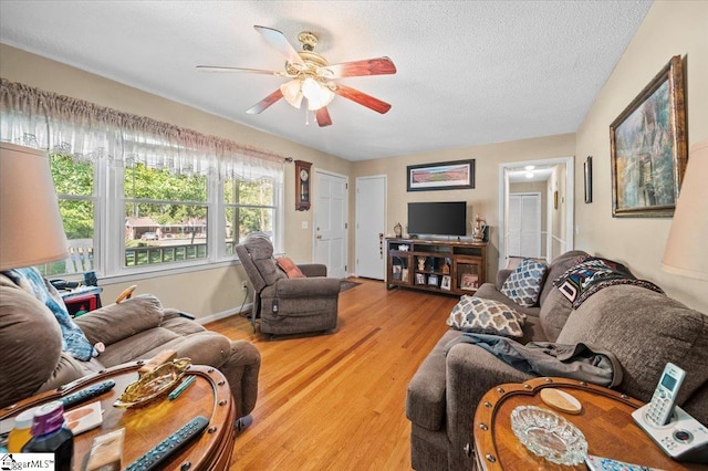 living room featuring light hardwood / wood-style floors, a textured ceiling, and ceiling fan