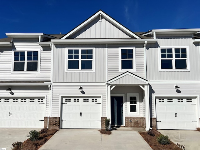 view of property featuring a garage, driveway, and brick siding