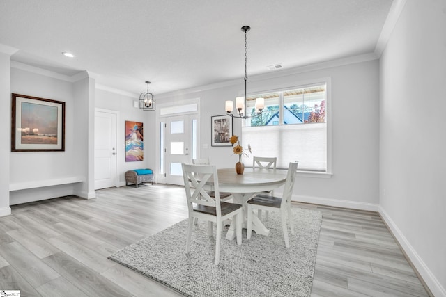 dining area featuring light hardwood / wood-style floors, ornamental molding, a textured ceiling, and a chandelier