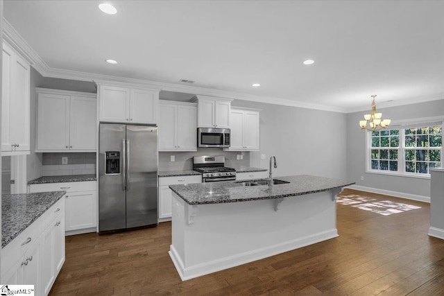 kitchen with appliances with stainless steel finishes, sink, dark stone counters, a notable chandelier, and dark hardwood / wood-style floors