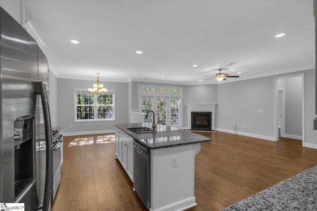 kitchen with dark wood-type flooring, dark stone countertops, sink, white cabinets, and appliances with stainless steel finishes