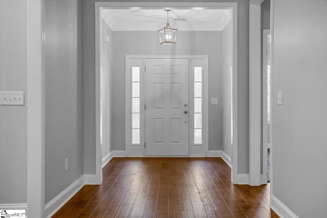 entrance foyer featuring dark wood-type flooring, ornamental molding, and an inviting chandelier