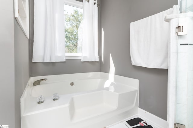 bathroom featuring tile patterned flooring, a tub, and plenty of natural light