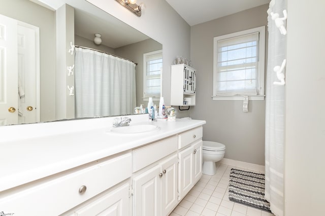 bathroom with vanity, a healthy amount of sunlight, toilet, and tile patterned flooring