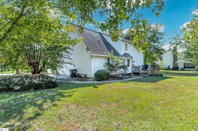 rear view of house with a deck, a yard, and a garage