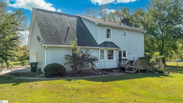 back of house featuring a deck, a yard, and a garage