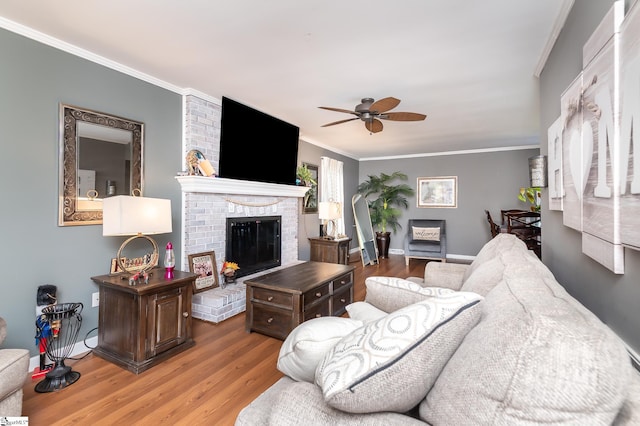 living room featuring ornamental molding, a fireplace, wood-type flooring, and ceiling fan