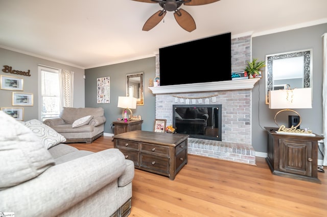 living room with ornamental molding, a fireplace, light hardwood / wood-style floors, and ceiling fan