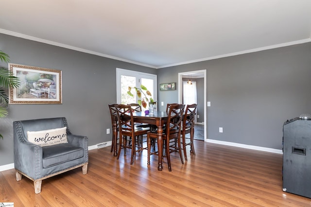 dining room with ornamental molding and hardwood / wood-style flooring