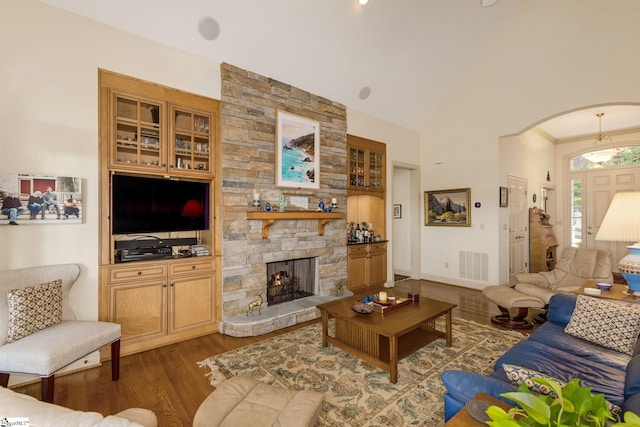 living room featuring dark wood-type flooring, ornamental molding, and a fireplace