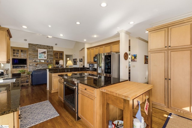 kitchen with appliances with stainless steel finishes, kitchen peninsula, dark stone countertops, ornamental molding, and dark hardwood / wood-style floors