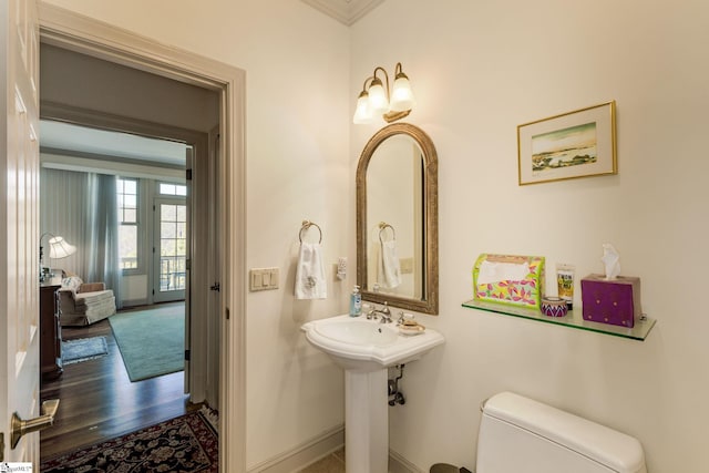 bathroom featuring toilet, hardwood / wood-style floors, and ornamental molding