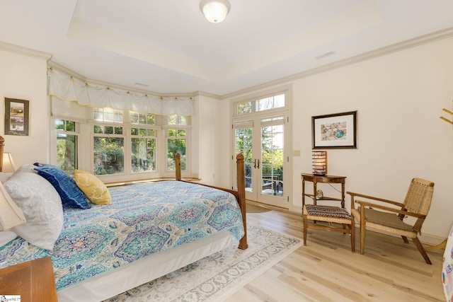 bedroom with access to outside, french doors, light wood-type flooring, and a raised ceiling