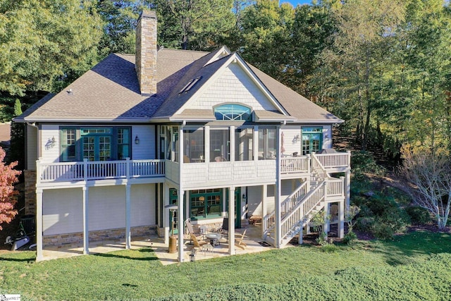 back of property with a patio, a sunroom, and a lawn