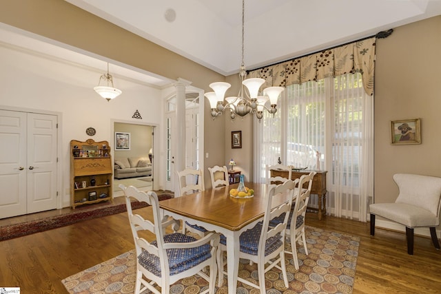 dining space with an inviting chandelier, dark hardwood / wood-style floors, and decorative columns