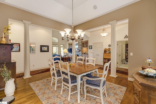 dining area featuring hardwood / wood-style flooring, a chandelier, and ornate columns