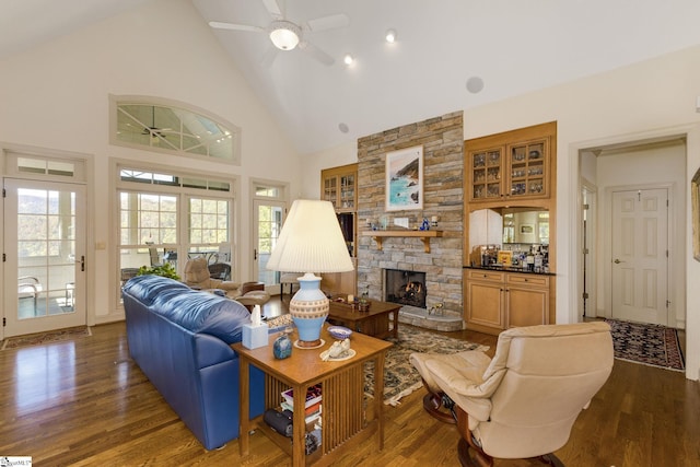 living room featuring dark hardwood / wood-style flooring, a fireplace, high vaulted ceiling, and ceiling fan