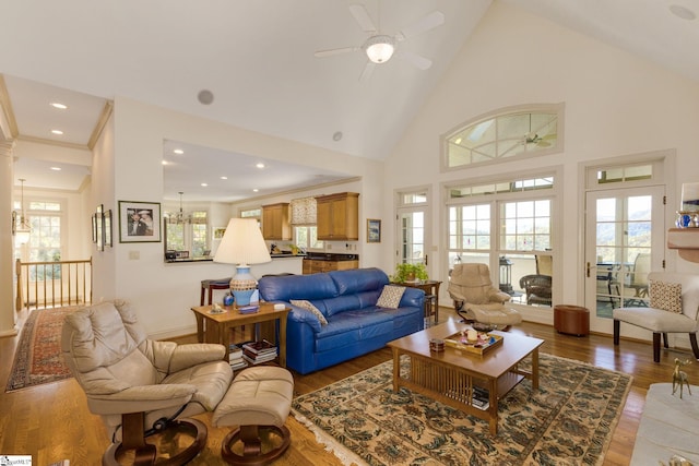 living room featuring high vaulted ceiling, a healthy amount of sunlight, ceiling fan with notable chandelier, and hardwood / wood-style floors