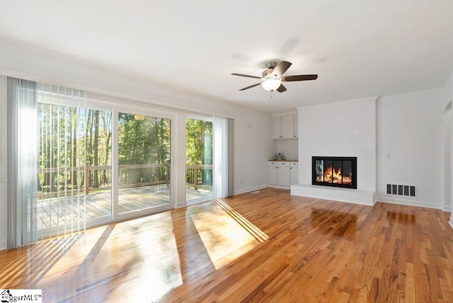 unfurnished living room with light hardwood / wood-style floors, ceiling fan, and a brick fireplace