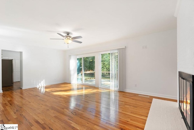 unfurnished living room with a fireplace, hardwood / wood-style flooring, and ceiling fan