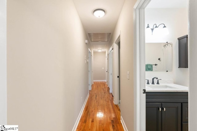 hallway with sink and light wood-type flooring