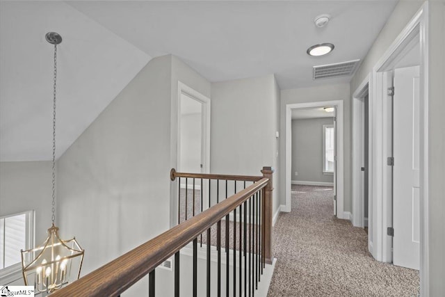 hallway featuring lofted ceiling, a chandelier, and carpet flooring