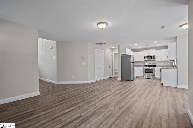 unfurnished living room with sink and light wood-type flooring