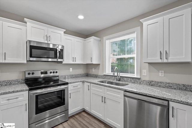 kitchen featuring white cabinetry, light stone counters, appliances with stainless steel finishes, and sink