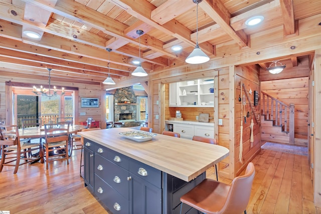 kitchen featuring light hardwood / wood-style floors, blue cabinets, wooden walls, and pendant lighting