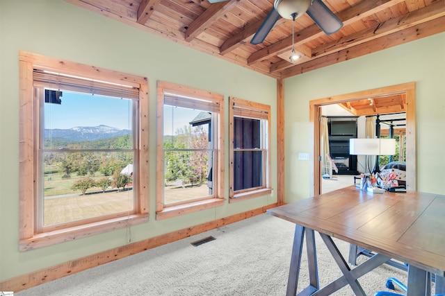 office space featuring a mountain view, a healthy amount of sunlight, wooden ceiling, and carpet