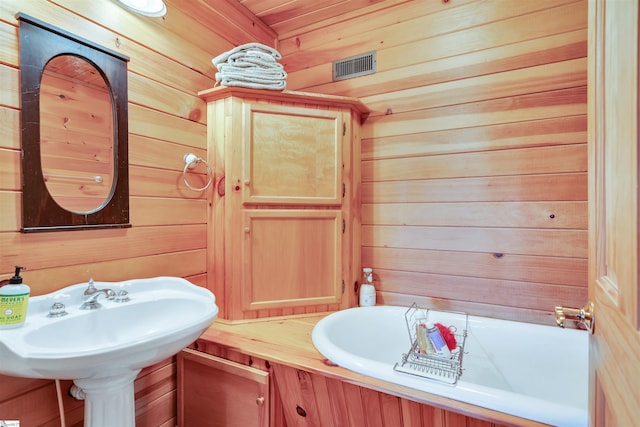 bathroom featuring wood ceiling, wooden walls, and sink