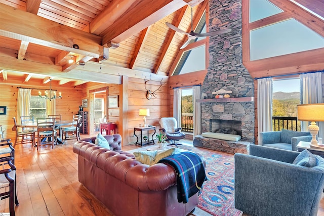 living room featuring a wealth of natural light, a fireplace, light hardwood / wood-style floors, and wood walls