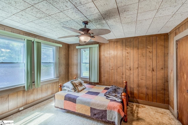 carpeted bedroom with wood walls and ceiling fan