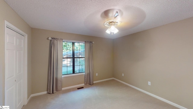 carpeted spare room featuring a textured ceiling and ceiling fan