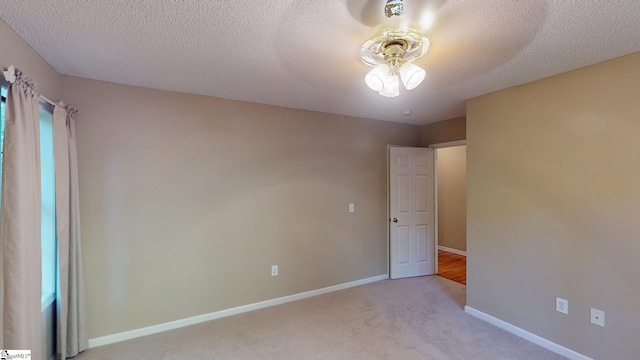 empty room with light carpet, a textured ceiling, and ceiling fan