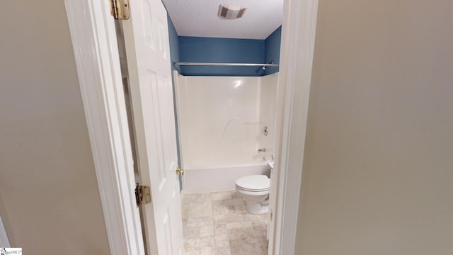 bathroom featuring toilet, shower / tub combination, and a textured ceiling