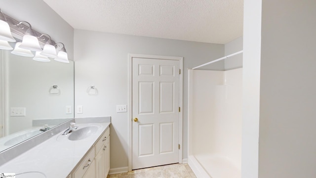 bathroom with vanity, a textured ceiling, and a shower