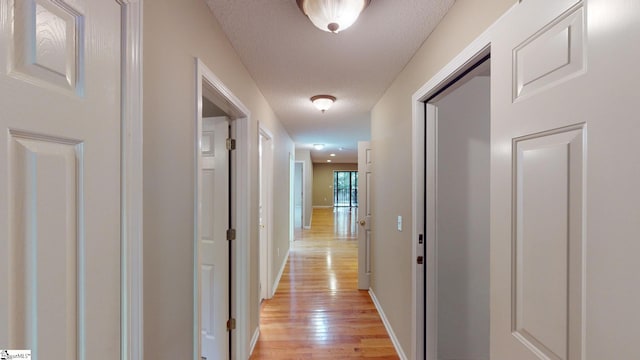 hall featuring light hardwood / wood-style flooring and a textured ceiling