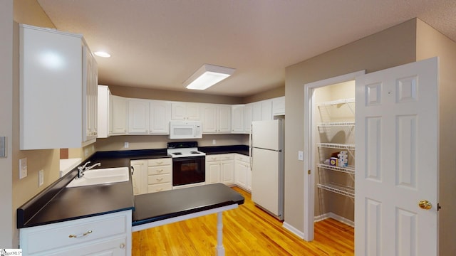 kitchen with sink, white cabinetry, light hardwood / wood-style flooring, and white appliances