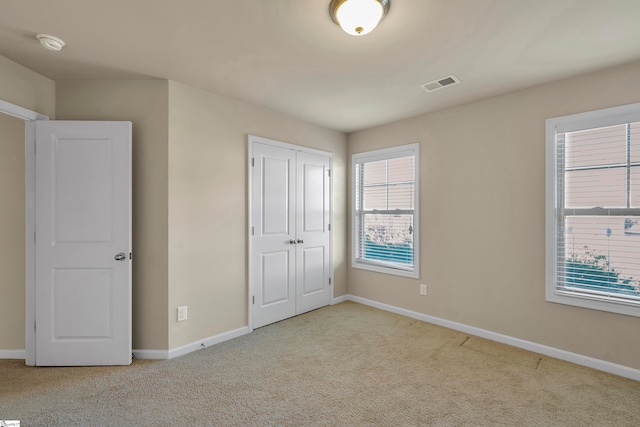 unfurnished bedroom with light colored carpet and a closet